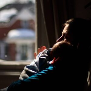 Maman tenant son bébé près d’une fenêtre – baby blues à Laval en Mayenne